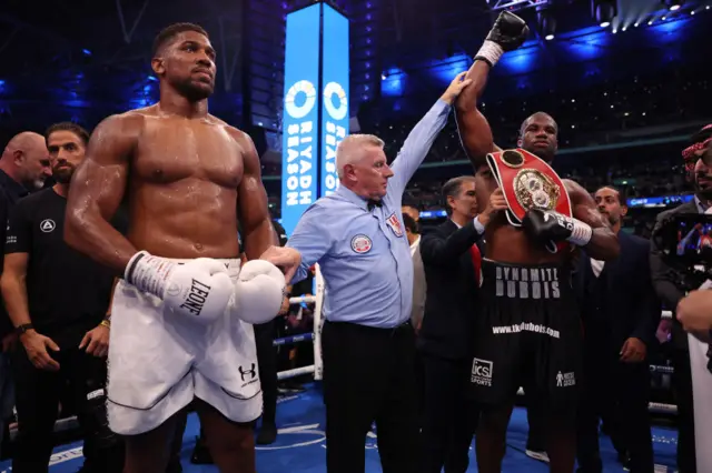 Daniel Dubois with his hand raised while standing next to Anthony Joshua