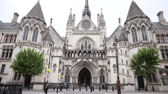 The front of the Royal Courts of Justice in London. A gothic-looking building with an arched entrance and various ornate turrets