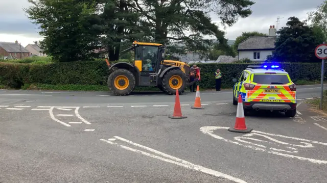 A road with a tractor and a police car.