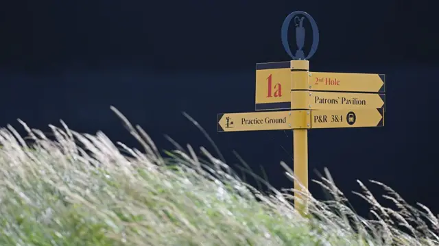 A shot of a signpost at the Open framed by long grass