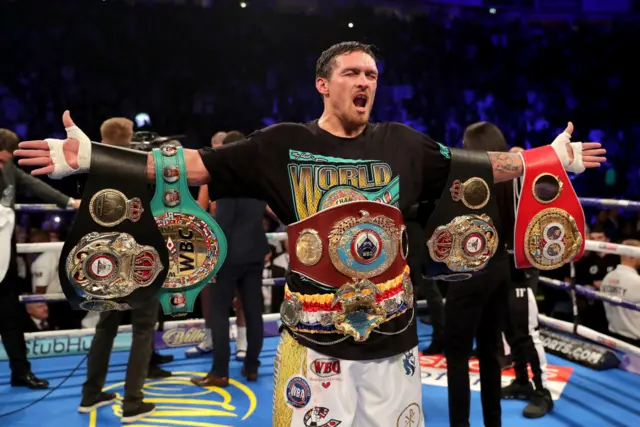 Oleksandr Usyk celebrating with cruiserweight world titles at Manchester Arena after beating Tony Bellew