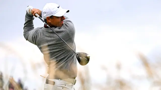 Rory McIlroy tees off behind some long grass