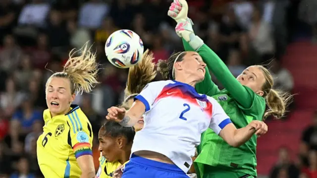 England's goalkeeper Hannah Hampton jumps for the ball next to England's defender Lucy Bronze