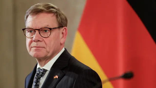 German Foreign Minister Johann Wadephul stands next to the German flag.