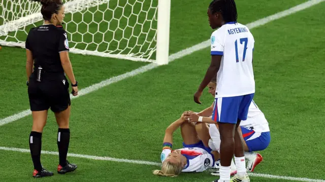 Leah Williamson of England is checked on by team mates Chloe Kelly and Michelle Agyemang after going down injured