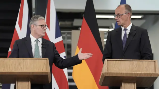 Prime Minister Sir Keir Starmer and German Chancellor Friedrich Merz hold a press conference. The German flag and Union Jack can be seen behind both men, who stand behind wooden pulpits.