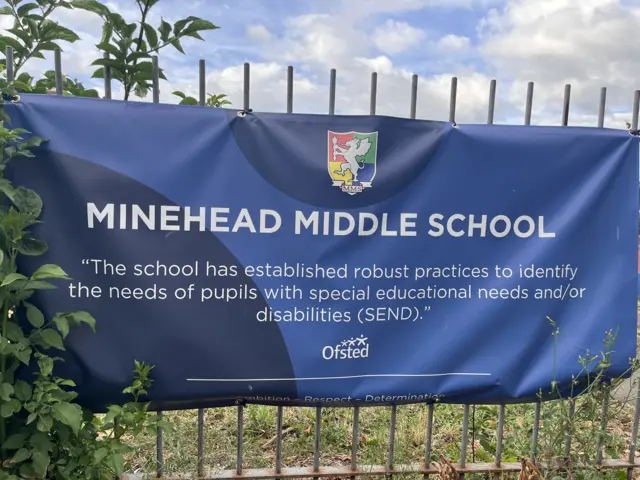 A canvas banner attached to railings reading: Minehead Middle School" and "The School has established robust practices to identify the needs of pupils with special educational needs and/or disabilities (send, Ofsted".