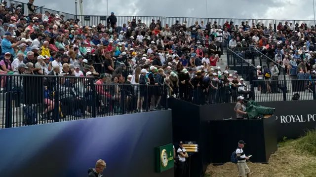 Fans trying to catch players golf balls as they exit the 18th green.