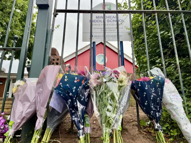Floral tributes outside Minehead Middle School's black gate.