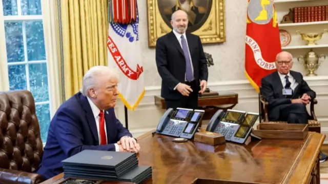 Trump sat behind desk, Rupert Murdoch sat on chair in Oval Office