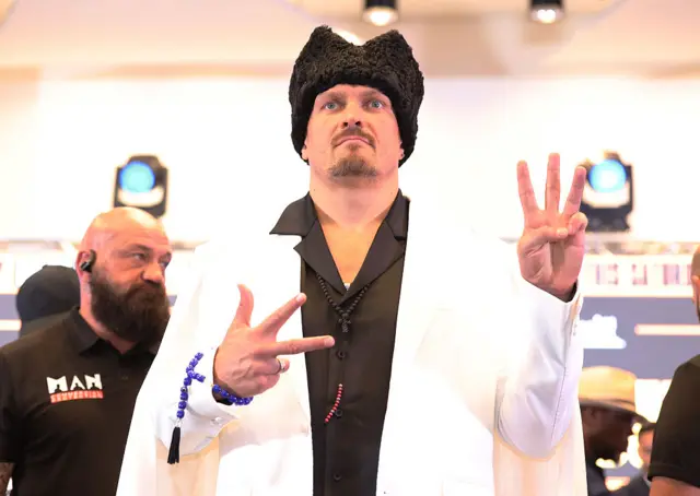 Oleksandr Usyk in white suit and black fur hat