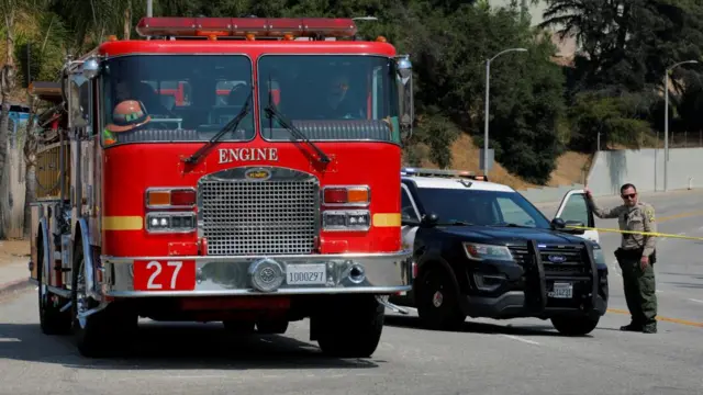 A fire truck and law enforcement care block the highway in Los Angeles, with an officer standing nearby
