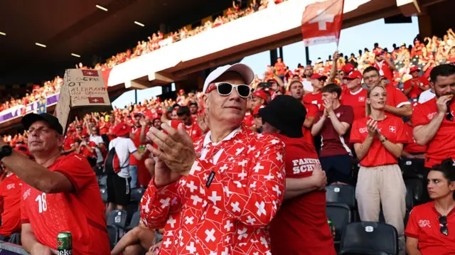 A fan of Switzerland enjoys the pre-match atmosphere whilst wearing a suit decorated with the flag of Switzerland