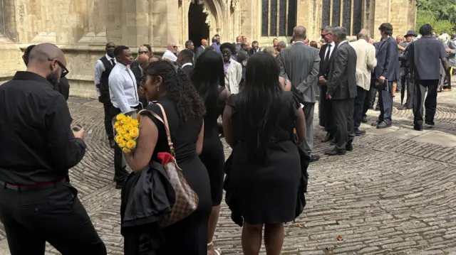 A large crowd gathering outside the church in Bristol. Most are dressed in black.