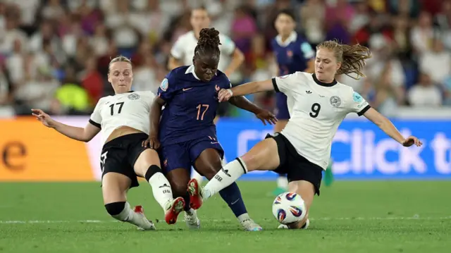 Sandy Baltimore of France is challenged by Franziska Kett and Sjoeke Nuesken of Germany