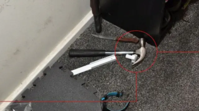 A hammer lying on a carpeted floor next to a watch and a knife.