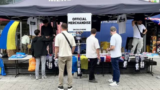 People standing in front of a stall selling merchandise for Oleksandr Usyk v Daniel Dubois