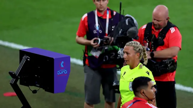Referee Tess Olofsson reviews the VAR monitor,