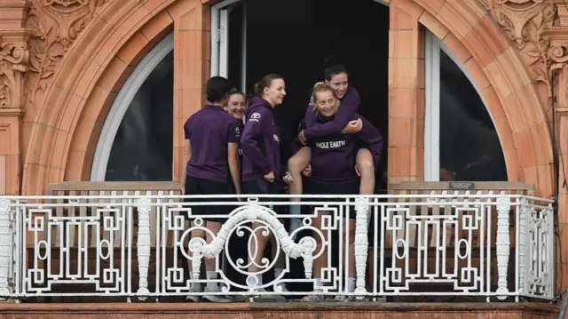 Em Arlott sits on top of Sophie Ecclestone of England as some rain falls at Lord's