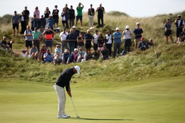 Scottie Scheffler putts on the green with spectators in the background
