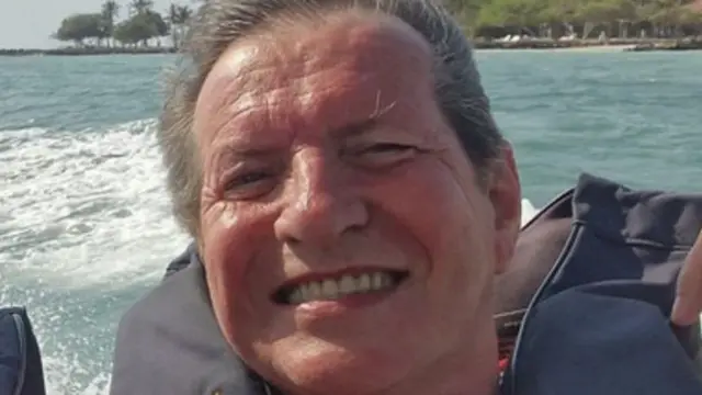 An image of a man wearing a red T-shirt and a lifejacket on a speedboat at a luxury resort.