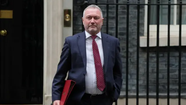 Steve Reed wears a suit with a red tie and leaves Downing Street.