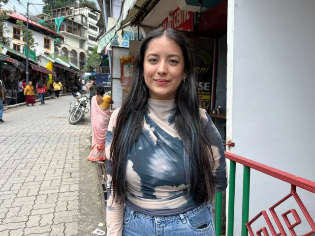 Pema Urgen stands in patterned t shirt and jeans