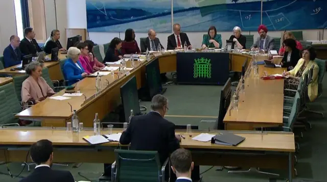Keir Starmer sits behind a long bench opposite a horse shoe shaped table, which has 14 people sat around it.