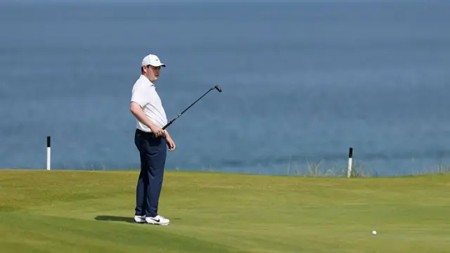Robert MacIntyre stands on a green with the ocean behind him