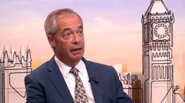 Nigel Farage in dark grey suit sits down in TV studio