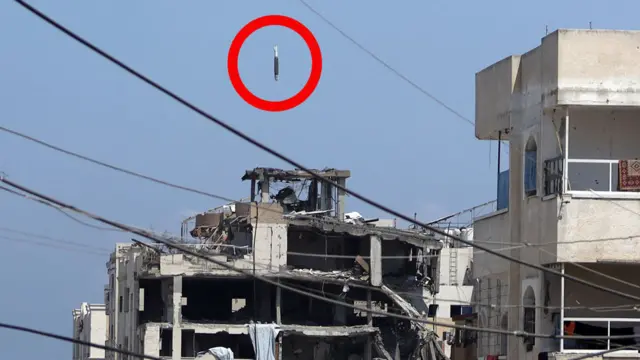 A missile is circled in red, mere metres from the top of a concrete high-rise building, which is already missing the exterior wall from the top four floors