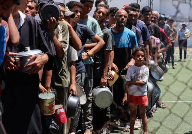 Palestinians gather to receive food from a charity kitchen in Nuseirat, central Gaza, on Sunday