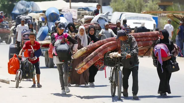People leaving on foot and bicycles with mattresses strapped to bikes