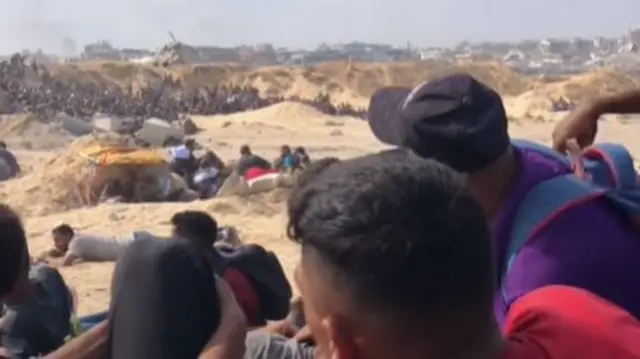 Men crouch and lie on ground among sandbanks as they try to reach aid in northern Gaza