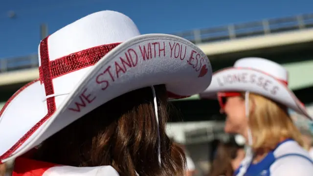 A fan of England is seen wearing a cowboy hat which reads "We stand with you Jess"