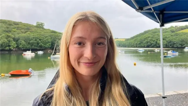 Hannah Smith stood by the river. she has long blonde hair and is wearing a dark coat.