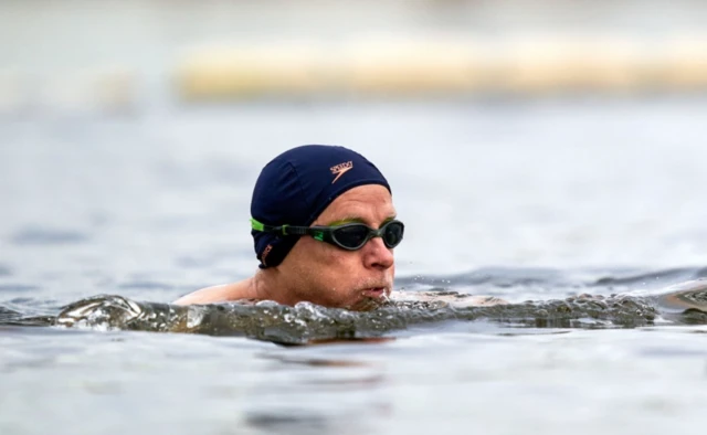 A person swimming in a blue hat and goggles.