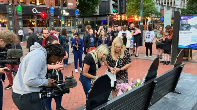 People placing flowers on a bench