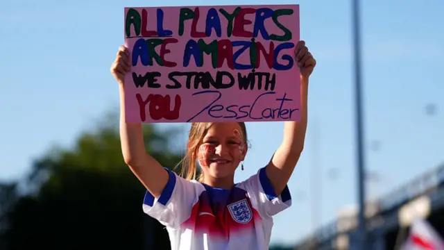 A fan of England holds up a sign showing support for Jessica Carter on her way to the stadium