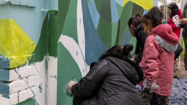 A family helping to paint a mural