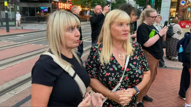 Two women wearing black tops stand on the street in Wolverhampton.