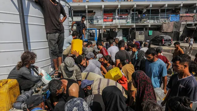 A crowd of people gather at a water distribution site in Gaza