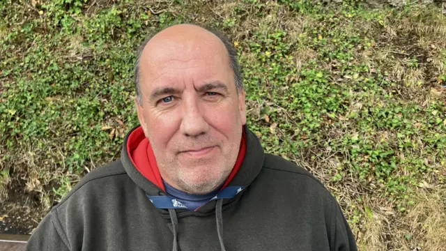 James Asser wearing a black hooded sweatshirt.