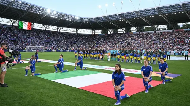 Players stand during the national anthems ceremony before the kick off