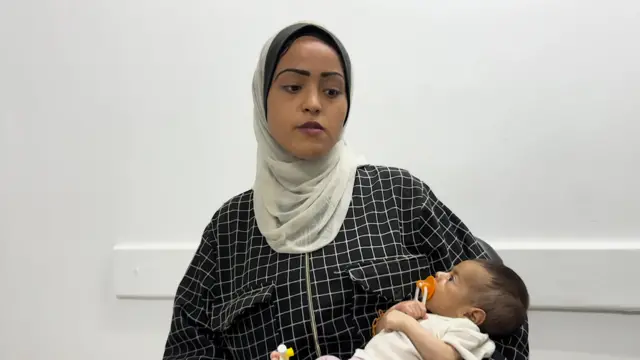 A 19-year-old mother holds her malnourished baby in a building in Gaza.