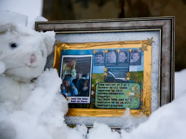 A small frame remembering Ethan Chapin, Madison Mogen, Xana Kernodle and Kaylee Goncalves sits in the snow outside of the residence where the four students were killed