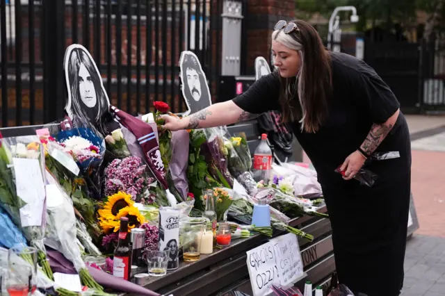 A fan lays a flower at the Black Sabbath bench