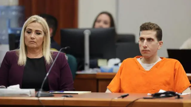 Bryan Kohberger wearing an orange jumpsuit sitting in the courtroom next to a woman wearing a purple coat