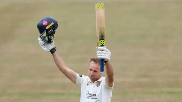 Tom Hartley raises his bat after scoring 100