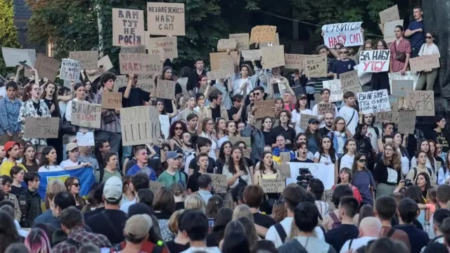 A group of mostly young people protesting in Lviv against the newly-passed law. Many of them are holding up banners written on cardboard.